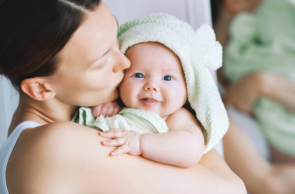 Een mama die haar baby liefdevol vasthoudt op de schouder in een badjas.