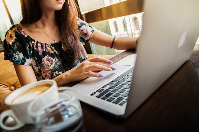 Vrouw werkt aan het laptop op een bureau met een kop koffie ernaast.