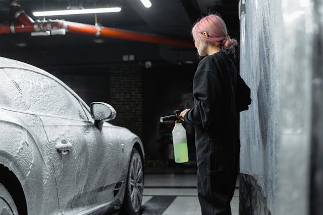 Vrouw die de auto aan het wassen is.