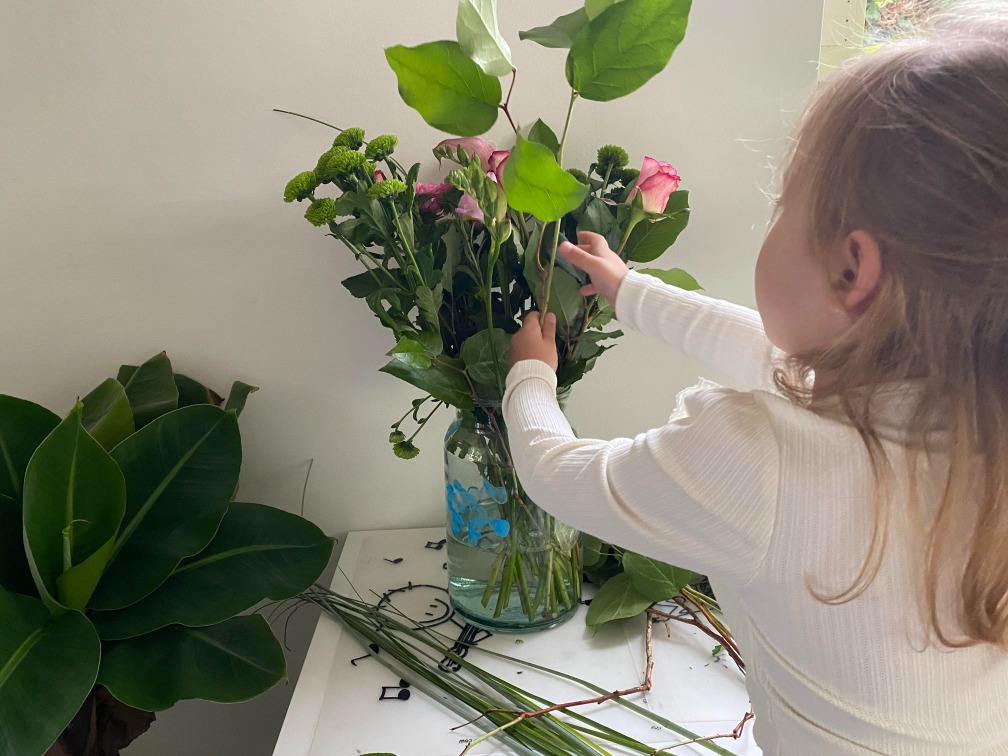 Evi stopt de bloemen in een vaas.