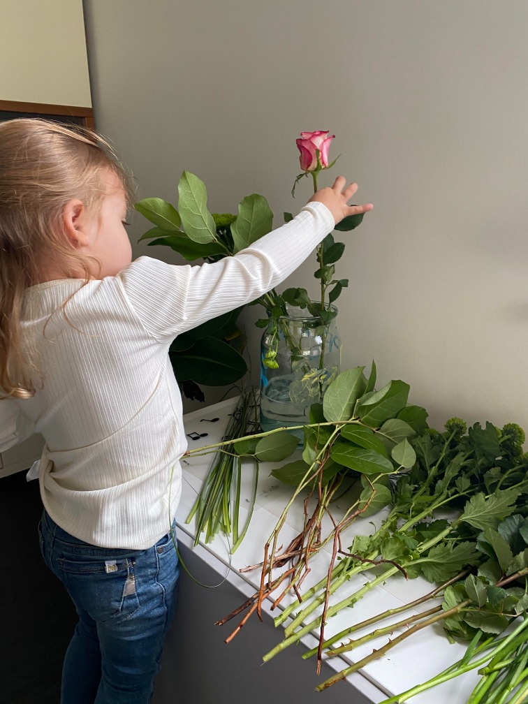 Evi stopt de bloemen in een vaas.