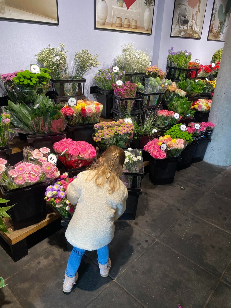 Evi zoekt bloemen uit in de bloemenwinkel.